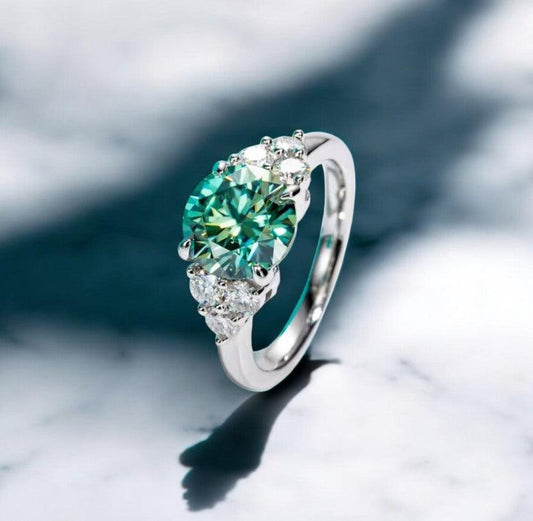 3 carat green moissanite engagement ring with VVS clarity displayed on a white marble countertop with a shadow behind it, made by russmoon