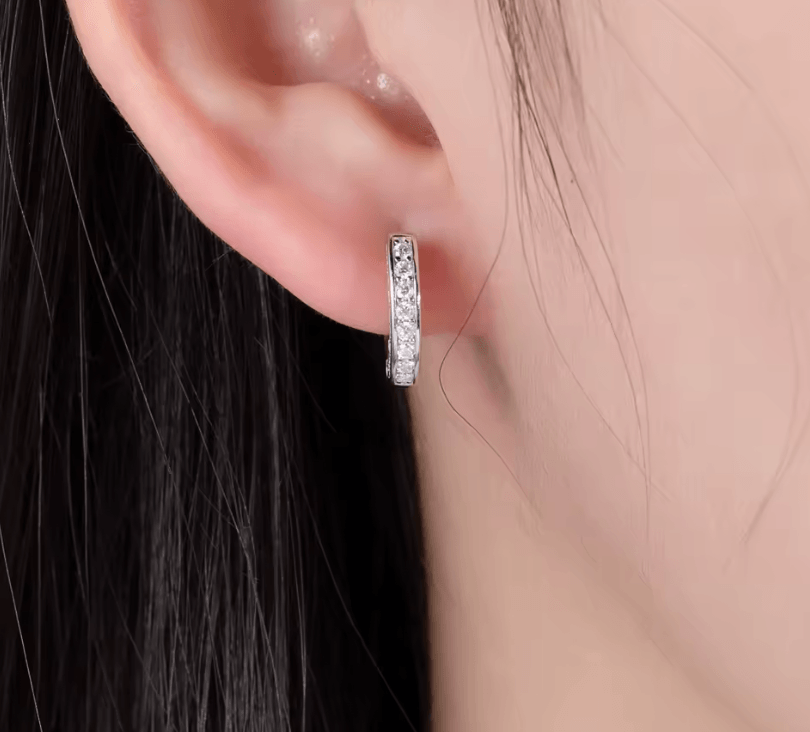 Moissanite hoop earrings with pave design, 925 sterling silver, displayed on a white marble counter, with light blue tones in the background, made by russmonco
