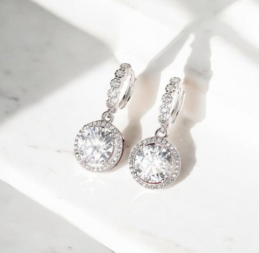 Round hoop moissanite earrings with 925 sterling silver showcased on a white marble countertop, elegant and timeless, made by russmoonco