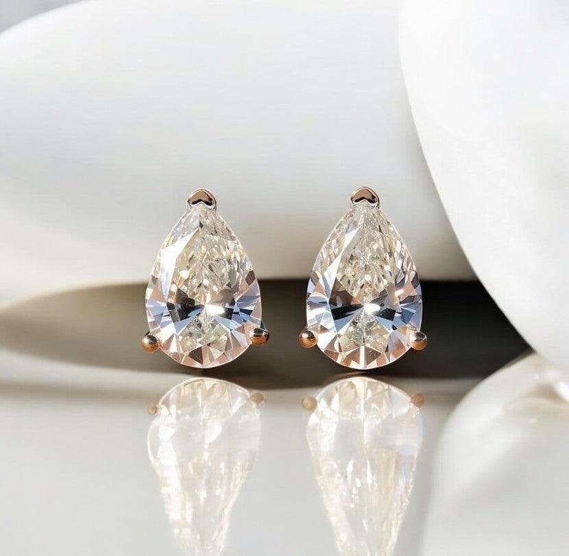 Waterdrop moissanite earrings with 925 silver showcased on a marble countertop with a light sandy vibe, made by russmoonco