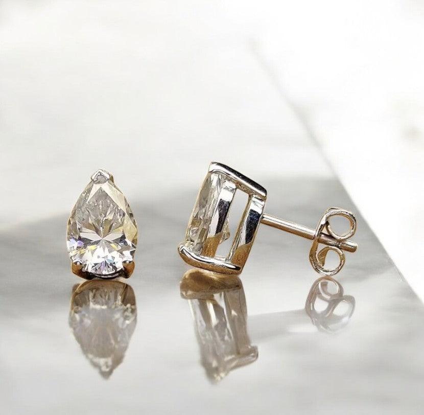 Waterdrop moissanite earrings with 925 silver showcased on a marble countertop with a light sandy vibe, made by russmoonco