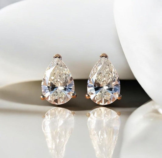 Waterdrop moissanite earrings with 925 silver showcased on a marble countertop with a light sandy vibe, made by russmoonco